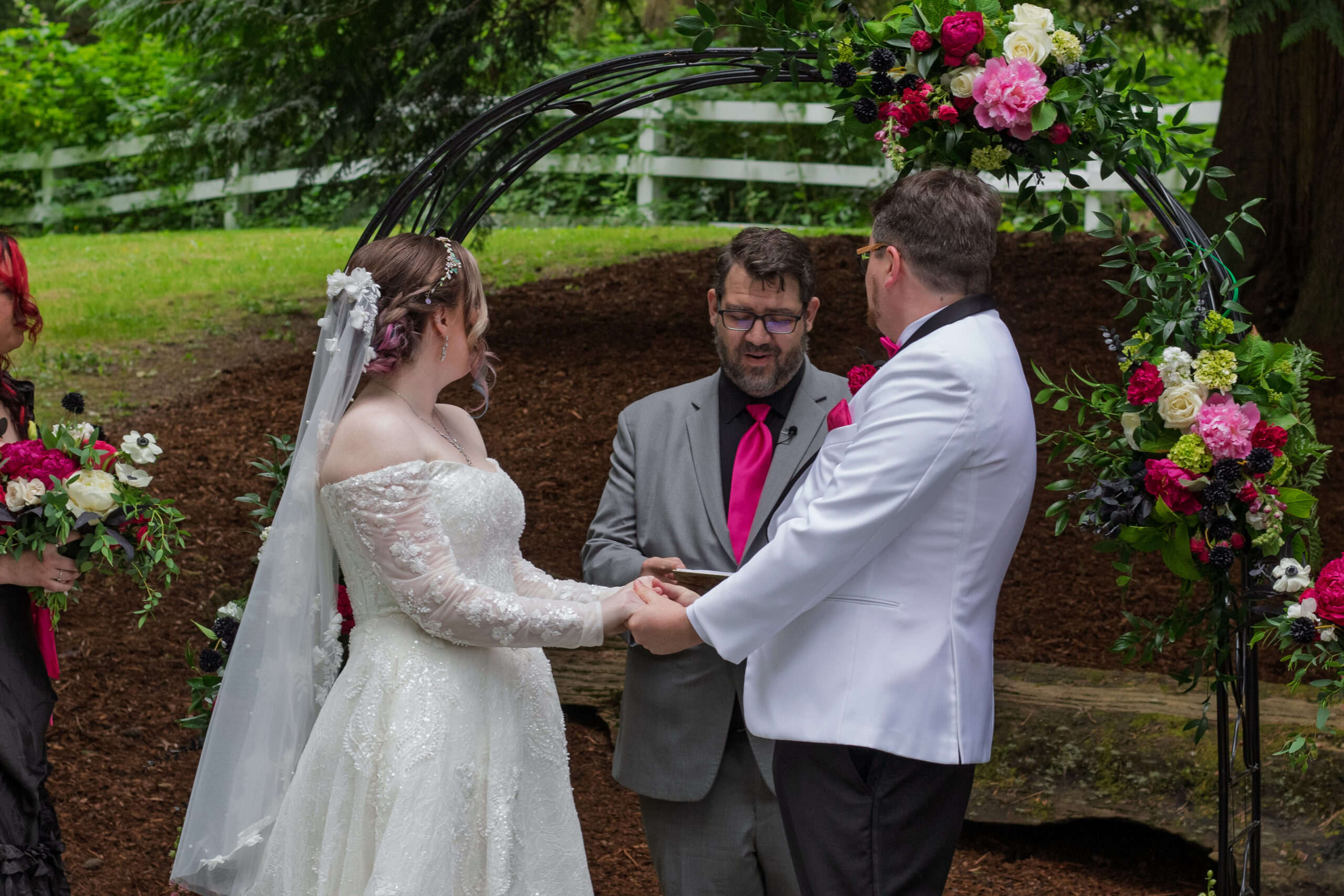 The bride and groom holding hands and looking to the officiant.