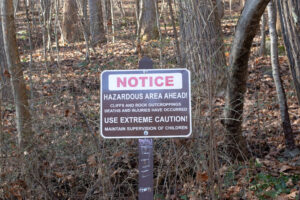 warning sign at the start of the purple trail at Rocks State park advising of the dangers of rocks and cliffs.