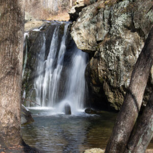 A long exposure photo of Kilgore Falls at Rocks State park, framed between two trees on the edge of the shot.